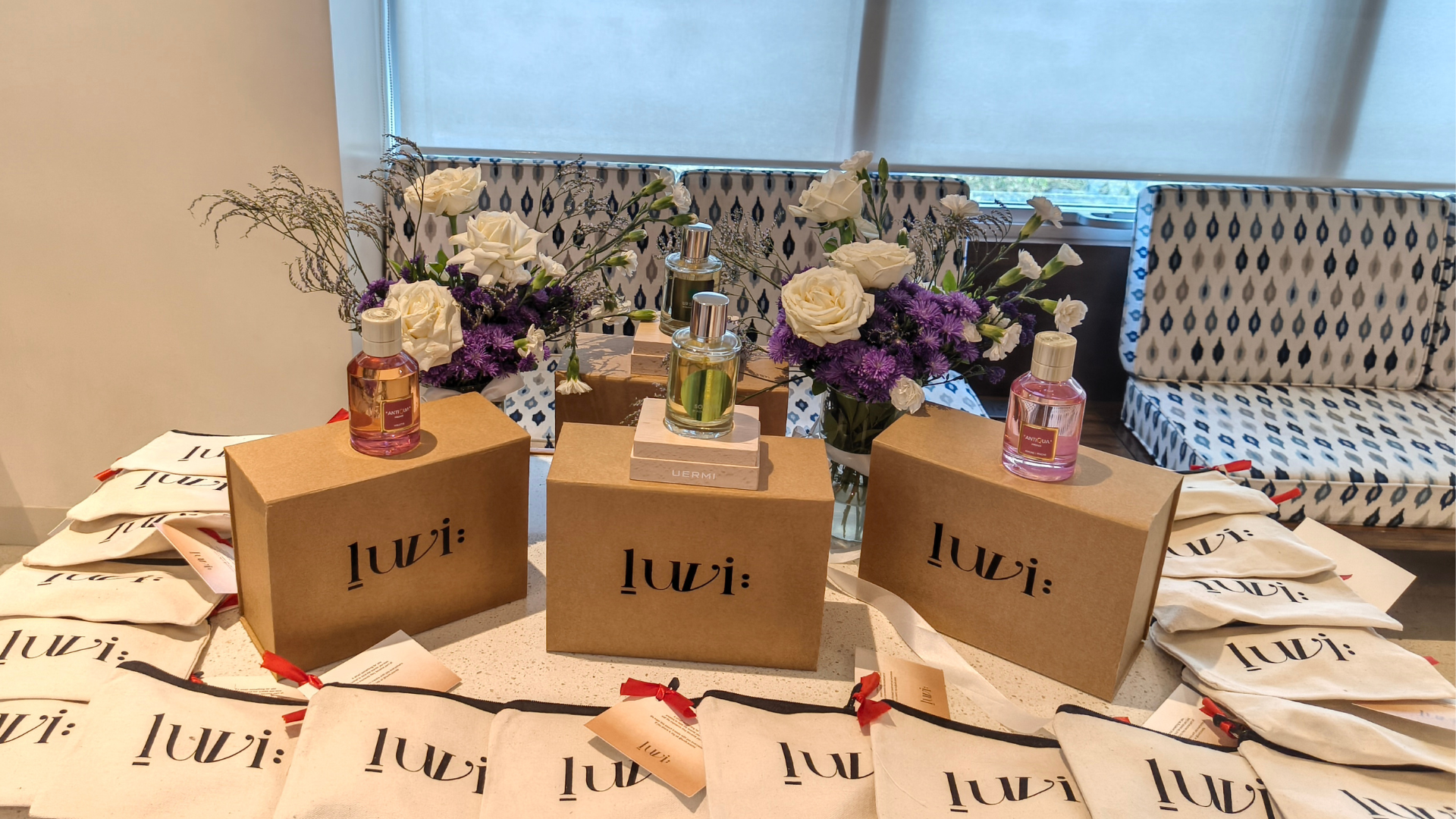 Luxury fragrance display by Luvih featuring premium perfume bottles, elegant floral arrangements, branded gift pouches, and curated niche perfumes showcased at an exclusive fragrance launch event in India.